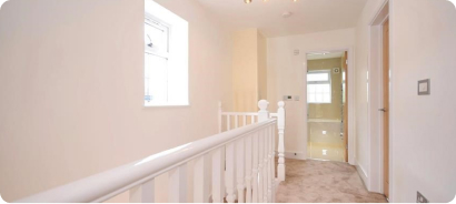 Bright upstairs landing with white balustrade after renovation